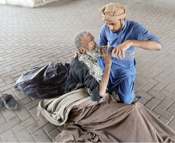 A picture shows a man giving water to a beggar.